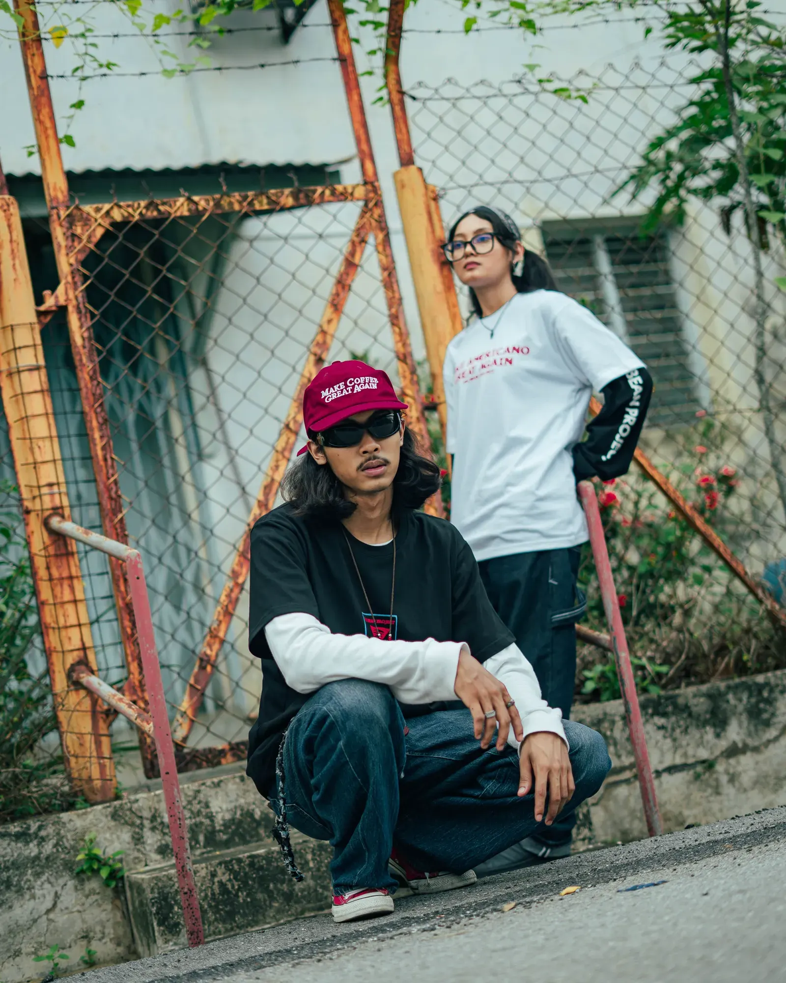Two people in TBP tees and the MCGA cap by a fence