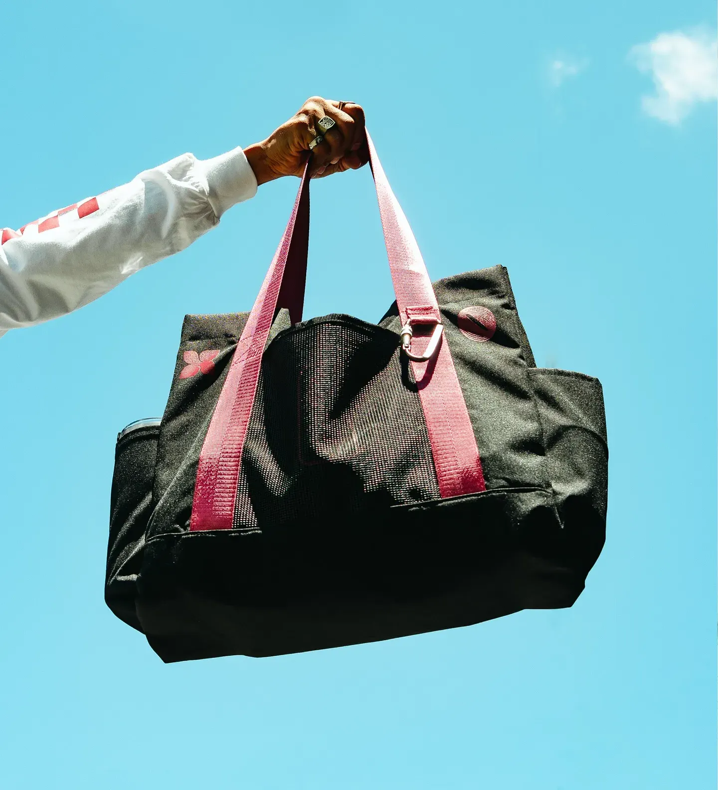 Black TBP totebag held up against the sky