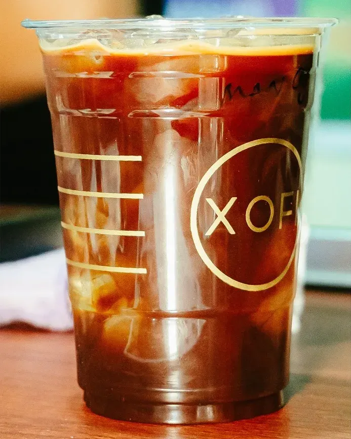 An iced americano in a XOFI cup on the bar